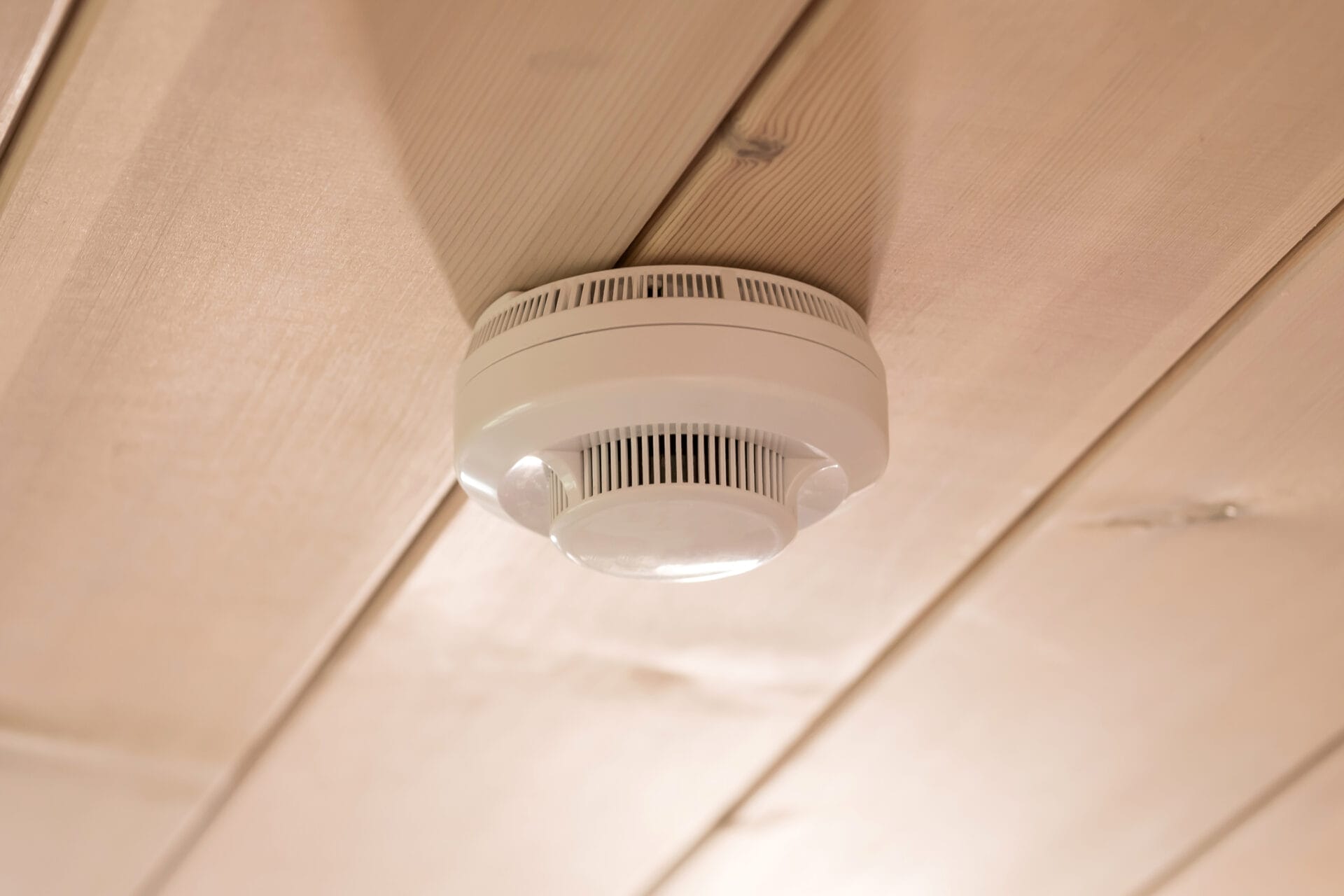 Carbon monoxide detector installed on a pine ceiling.