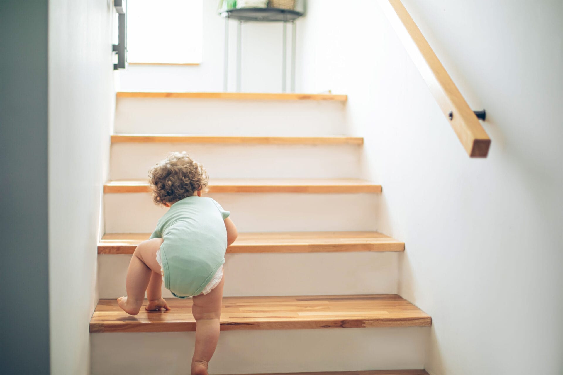 A baby crawling up wooden stairs