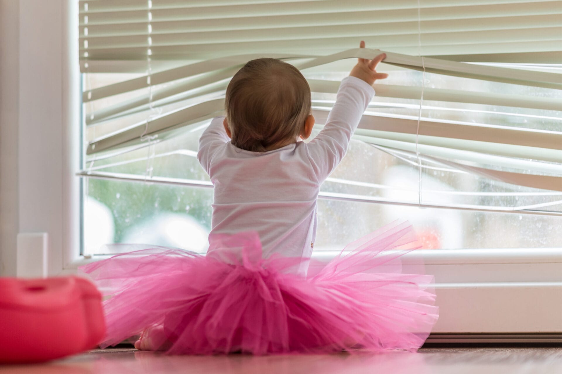 A baby playing with blinds