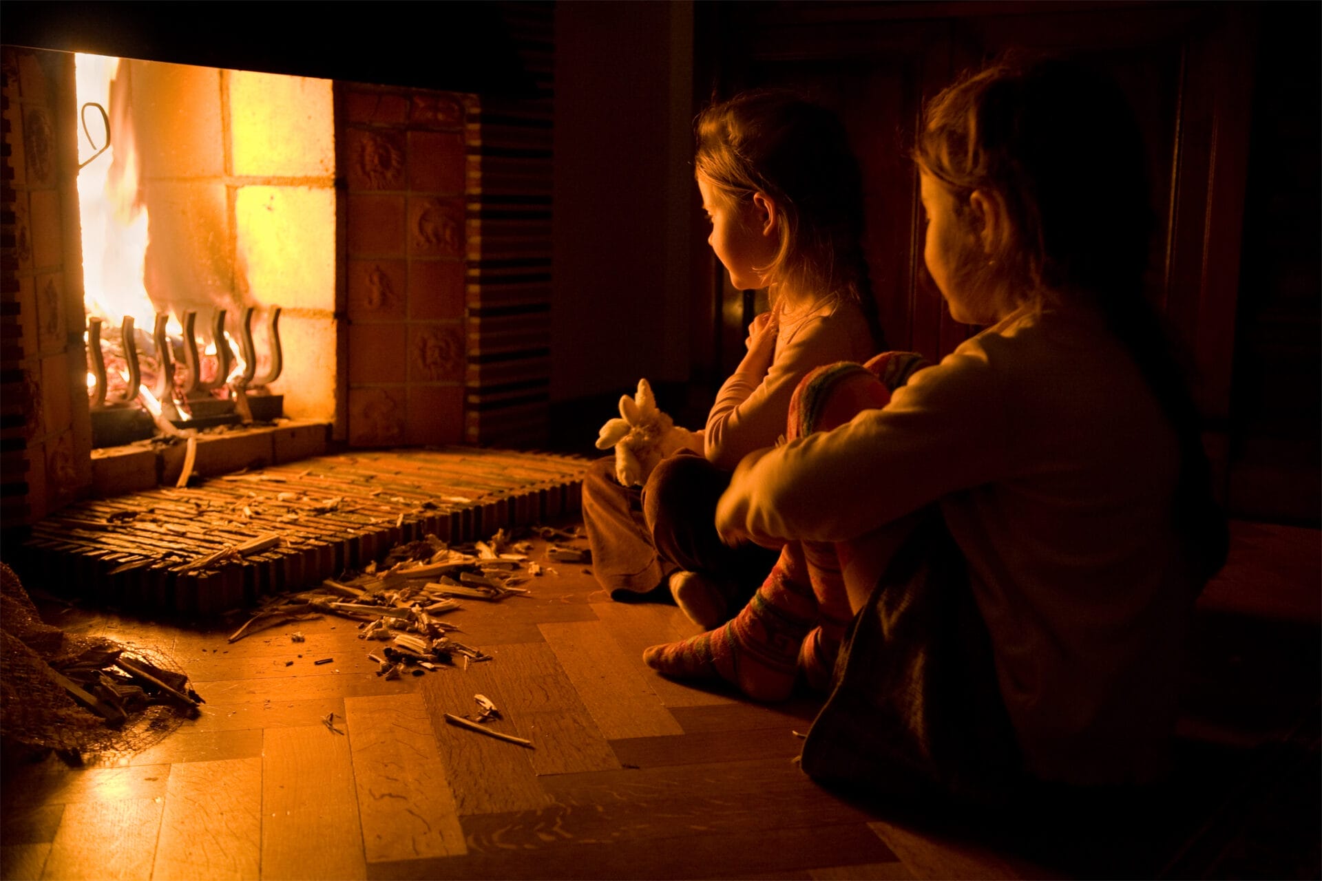 Two children sitting in front of an open fireplace