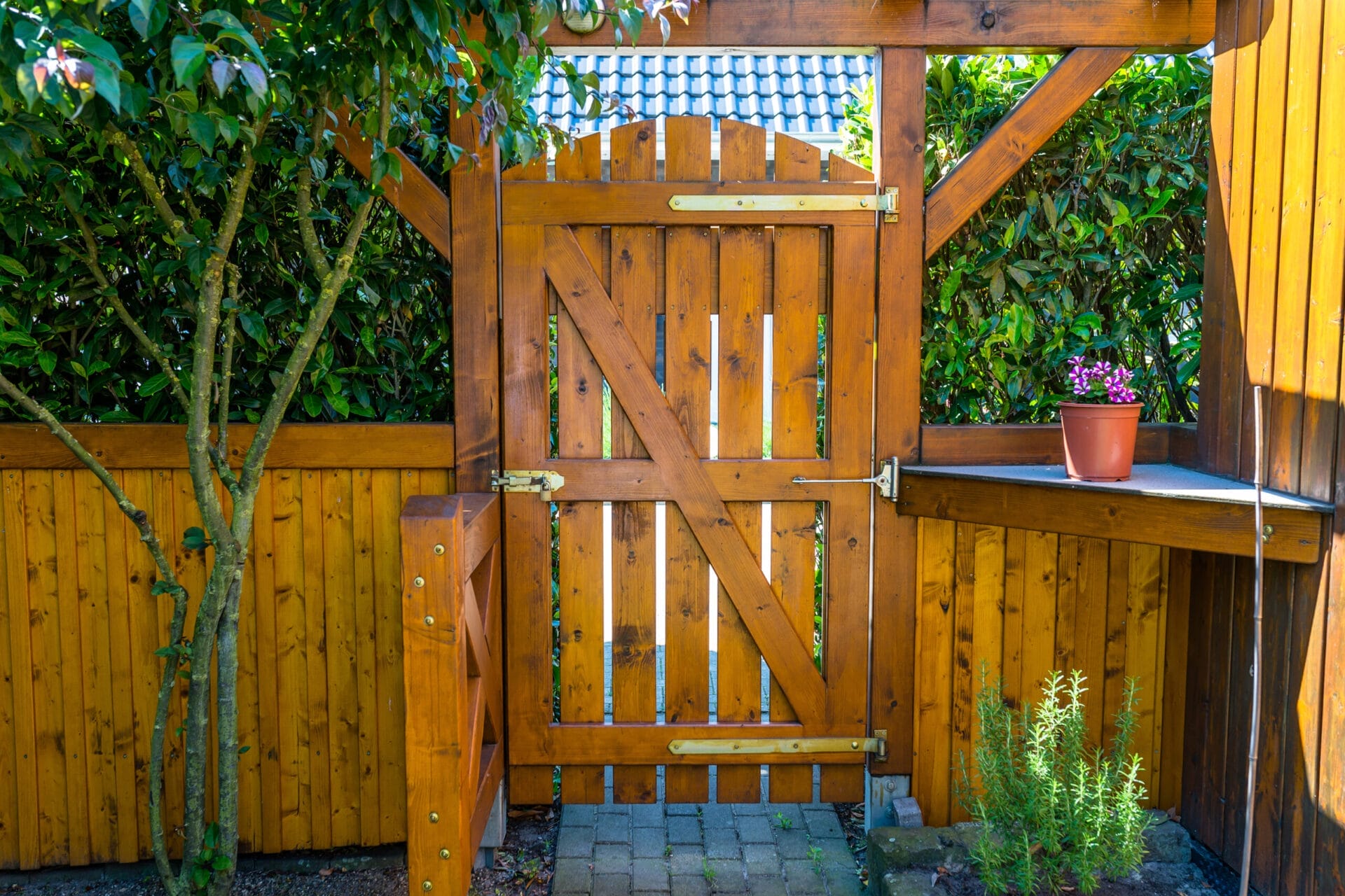 A stained wooden fence with a swinging door.