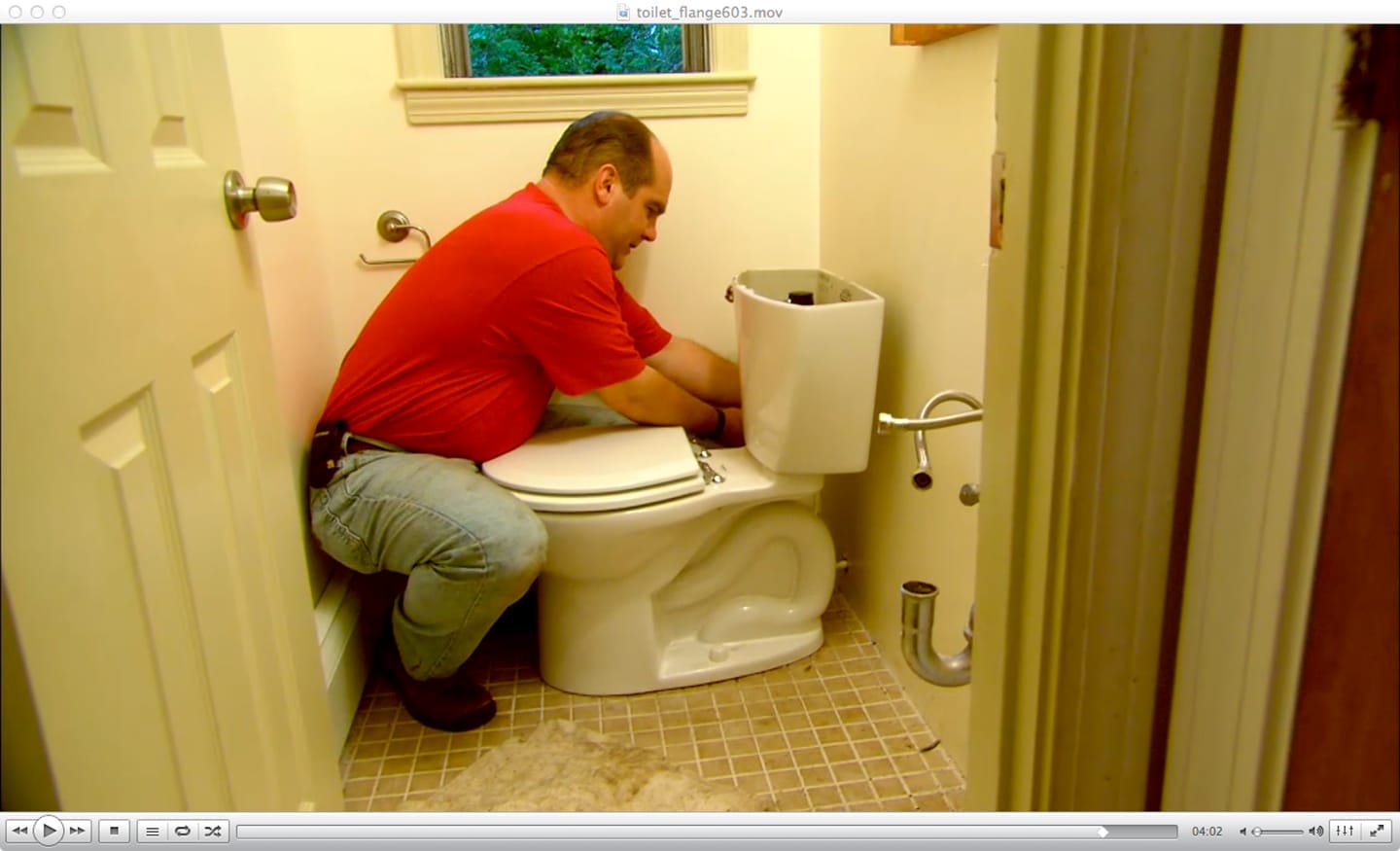A man working on a toilet with the lid removed.