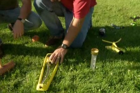 A man placing a sprinkler on a lawn.
