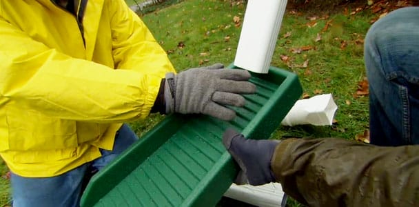 Two people holding a downspout system.