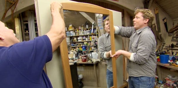 2 men installing a hanging mirror on a wall.