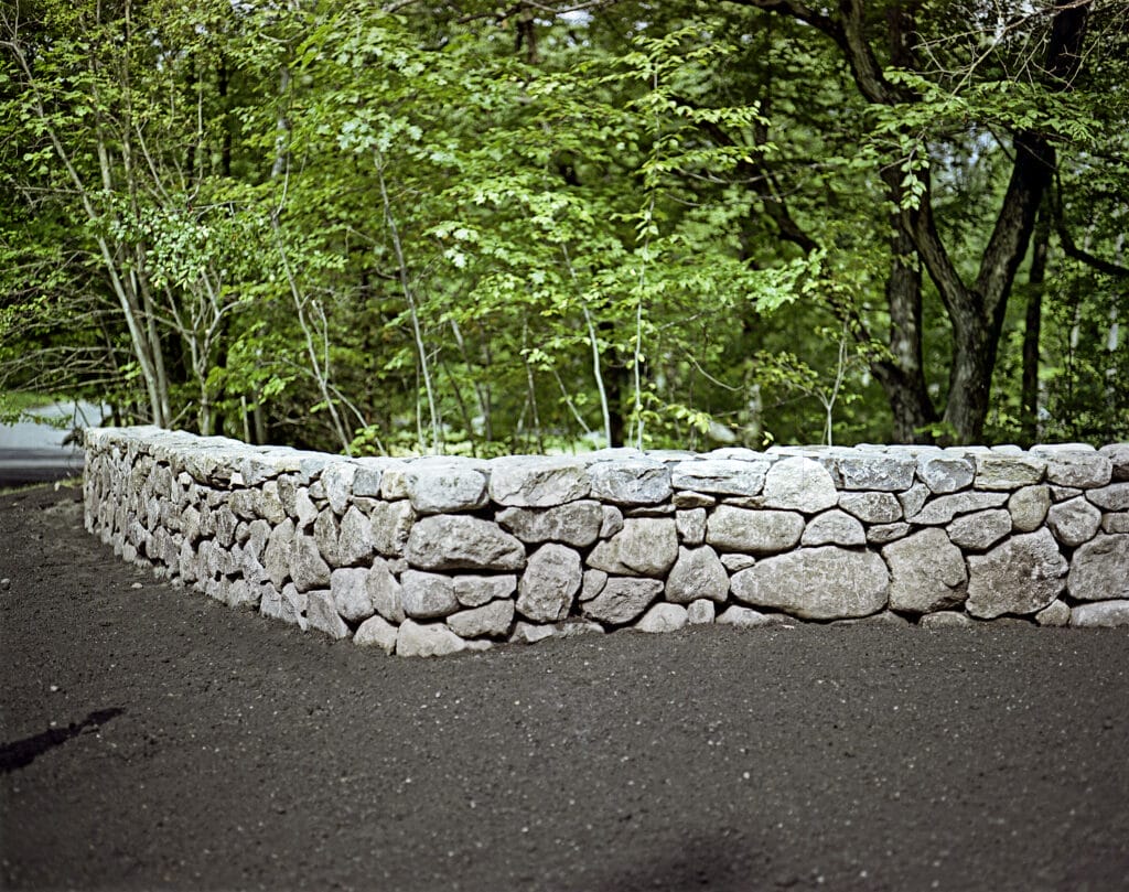 A stone wall in front of several trees.