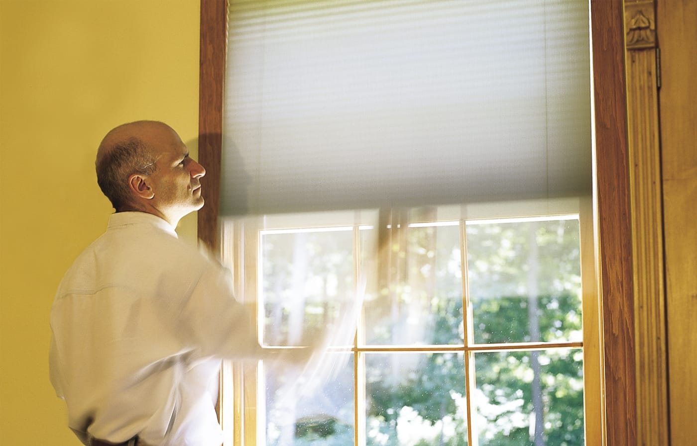 A man testing window shades to ensure they are operating correctly.
