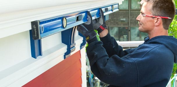 A man installing fiberglass gutters on a roof.