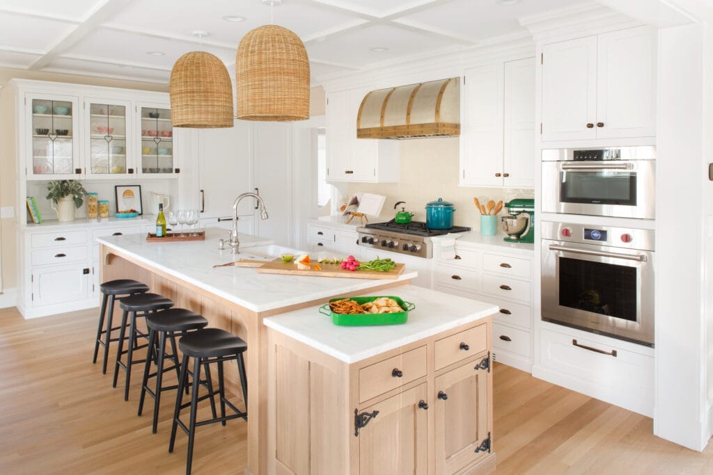 A kitchen island with a white countertop and black stools.