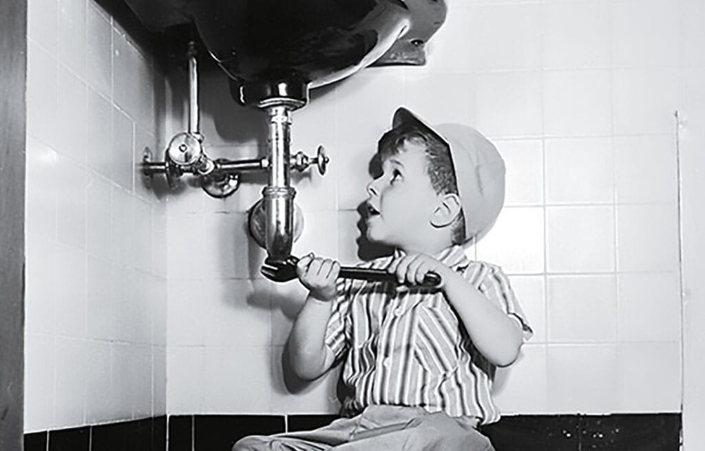 a little kid is trying to fix the pipes under a sink
