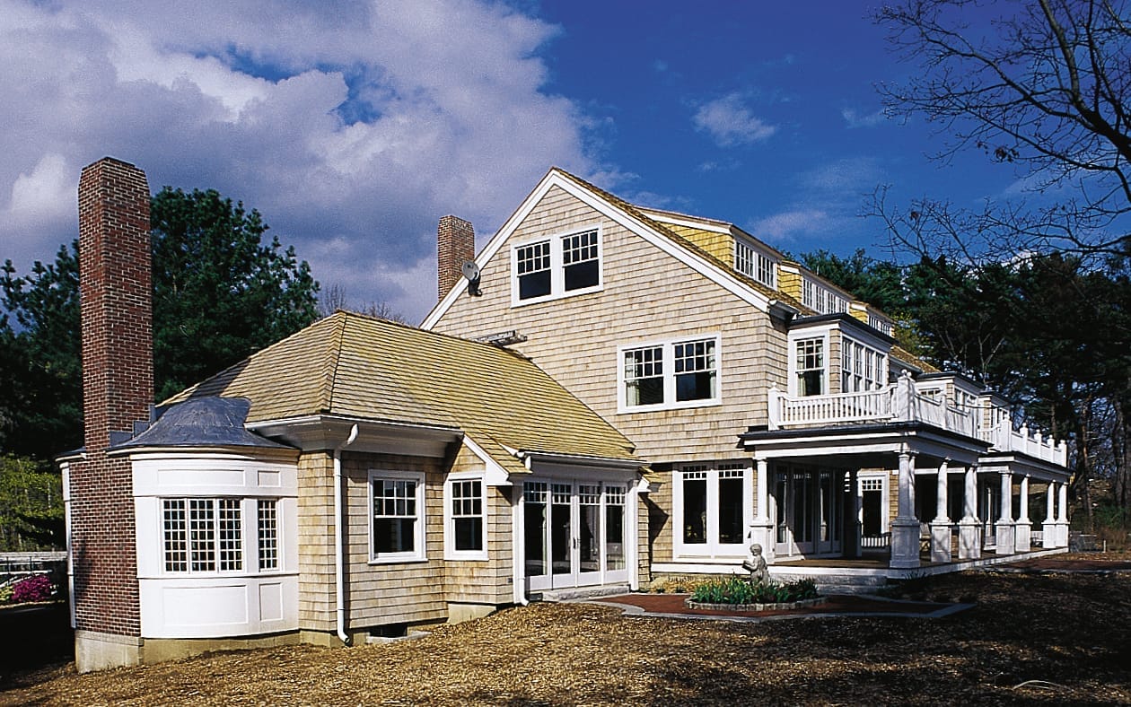A white home with a chimney and a lawn.
