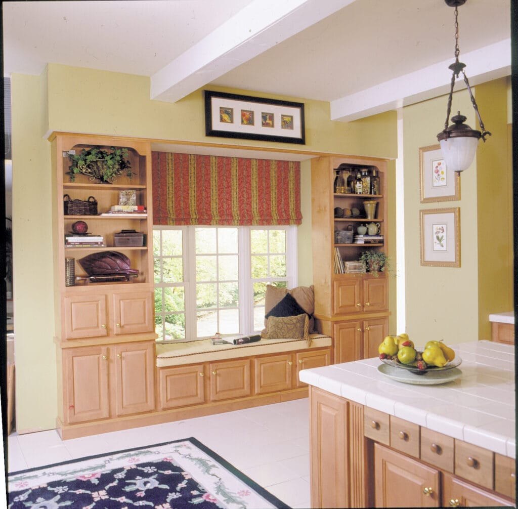 A cushioned window seat between two book cases.