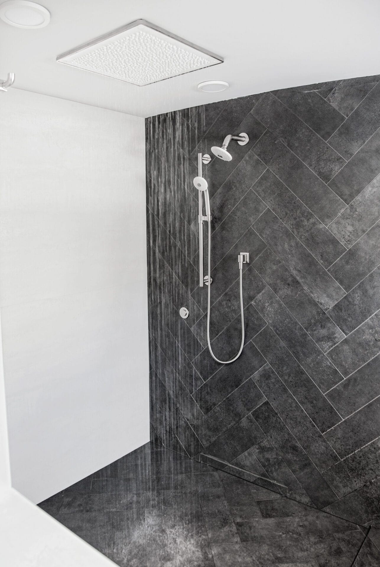 Master shower with herringbone tile pattern and low-profile drain.