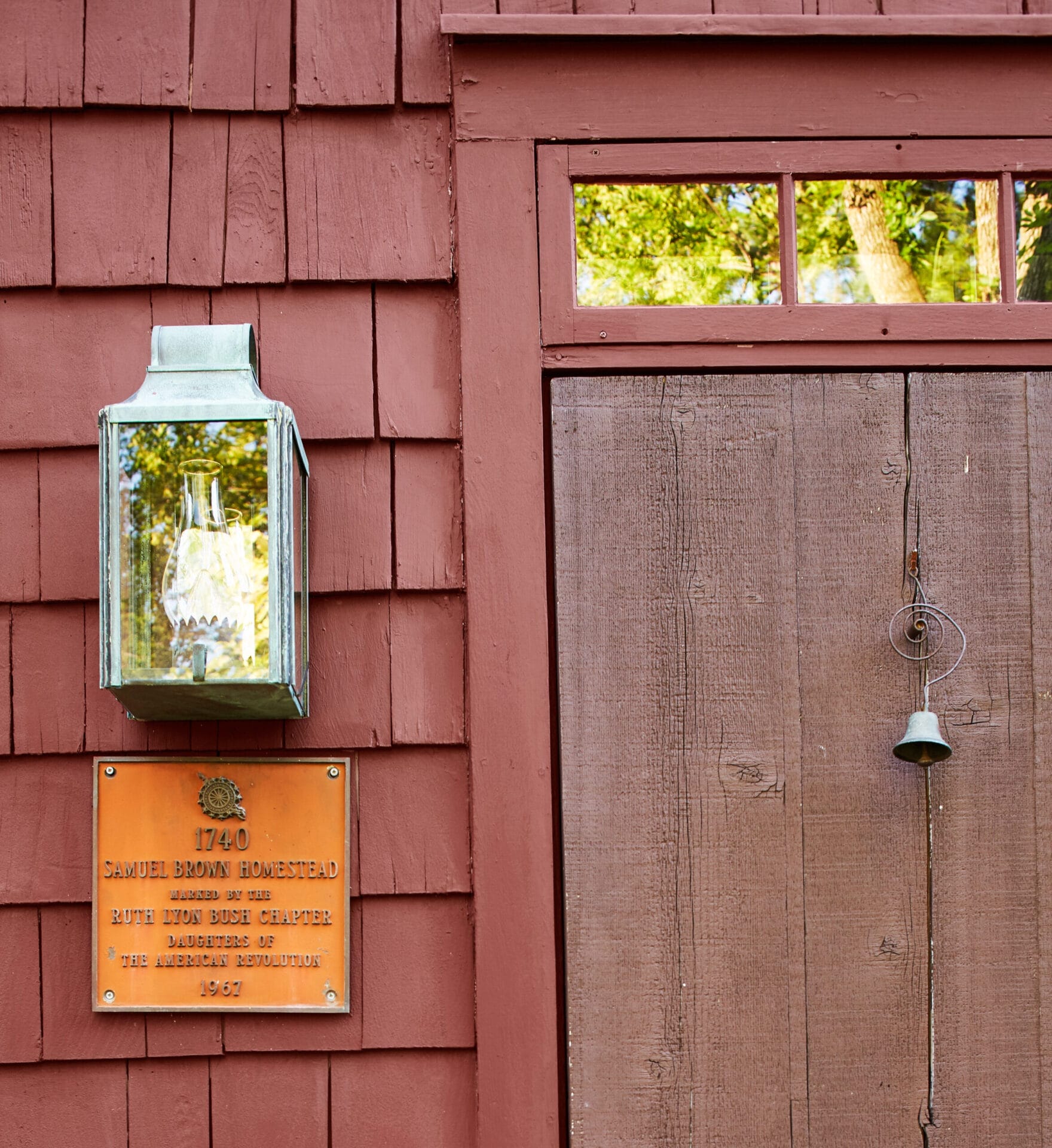 A hanging lantern and historical plaque outside of the house.