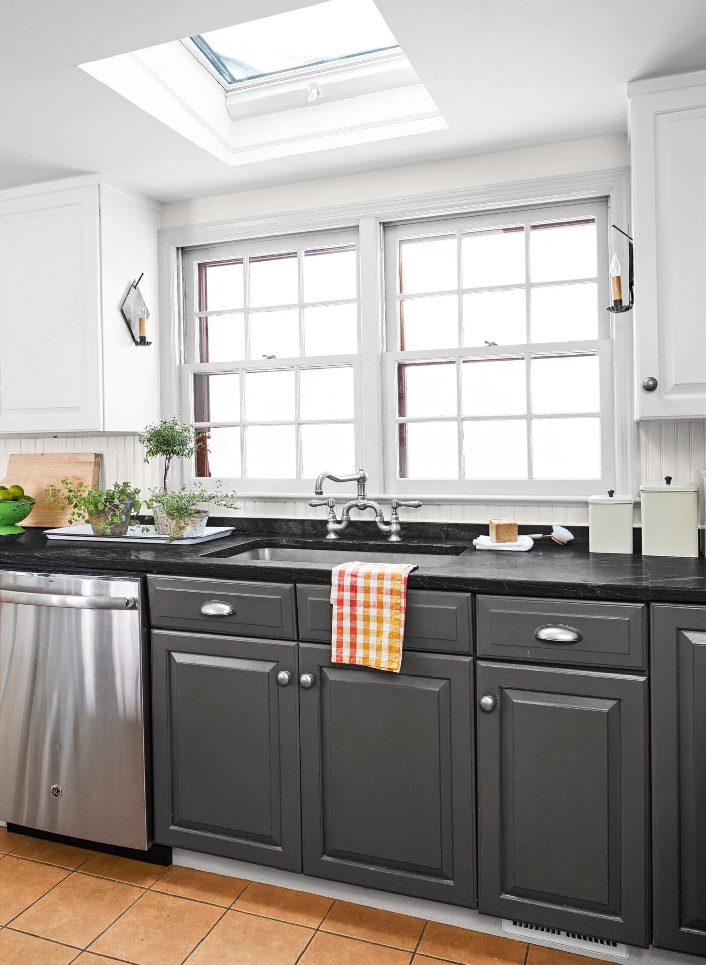 A kitchen sink area with a bridge faucet and windows.