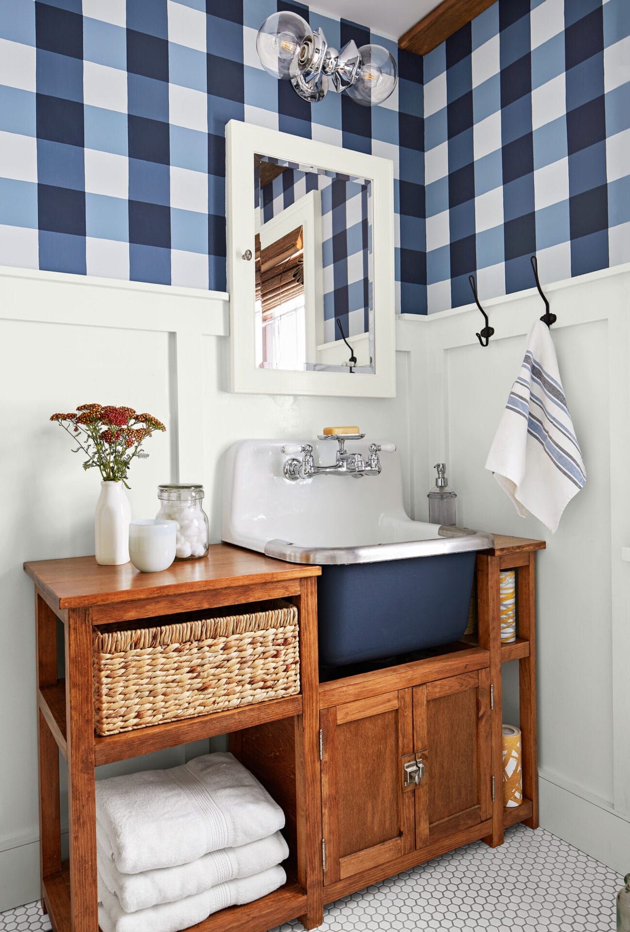 A bathroom with wainscoting and blue and white plaid wallpaper.