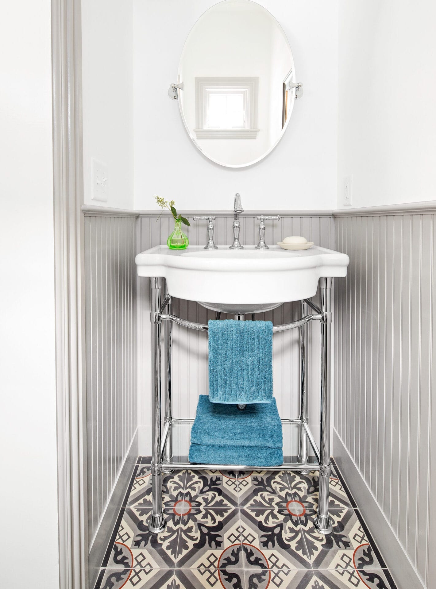 Powder room with patterned cement tile floor and beadboard wainscot.