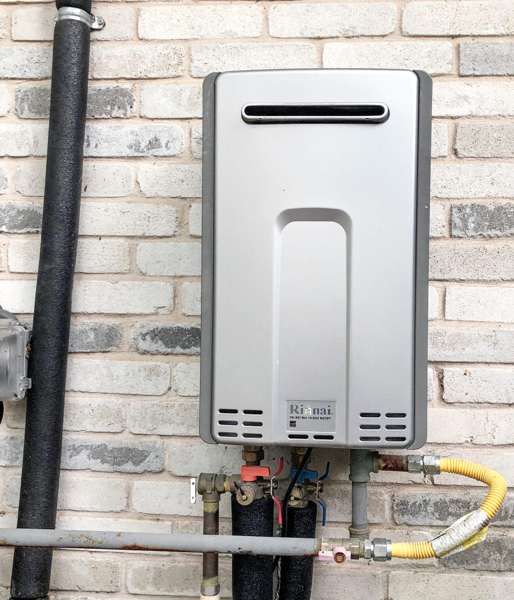 A tankless water heater attached to the outside of a house.