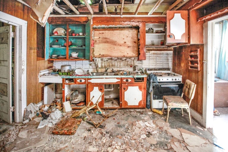 Deteriorated kitchen interior showing extensive damage.
