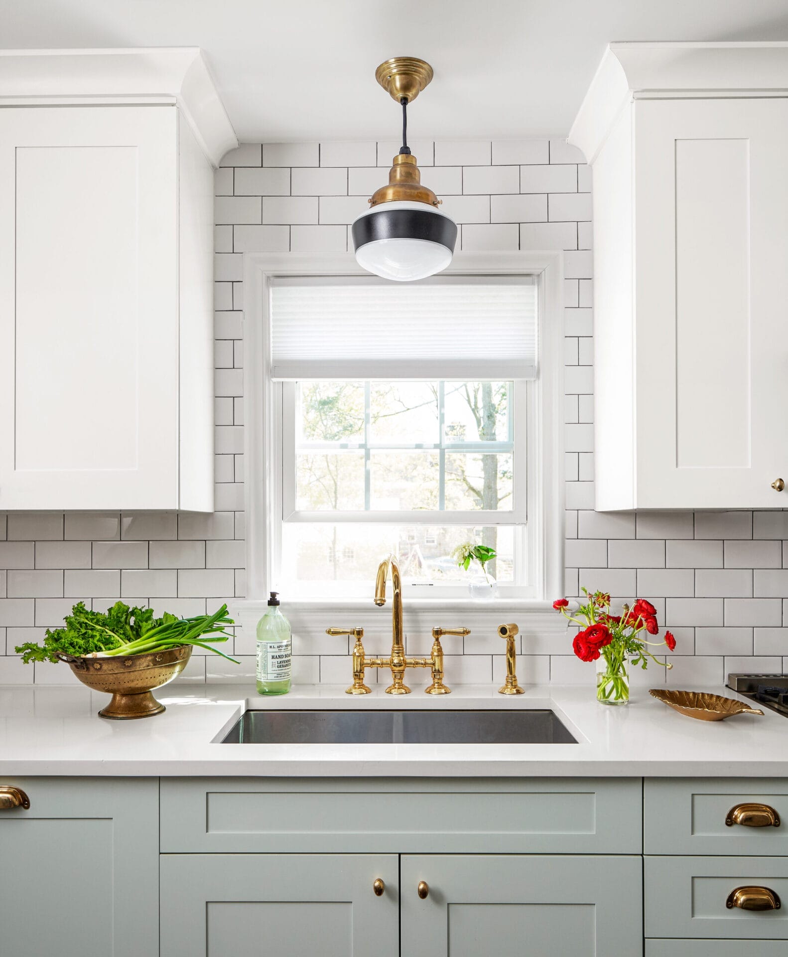 Brass kitchen faucet providing dramatic contrast against neutral white surfaces.
