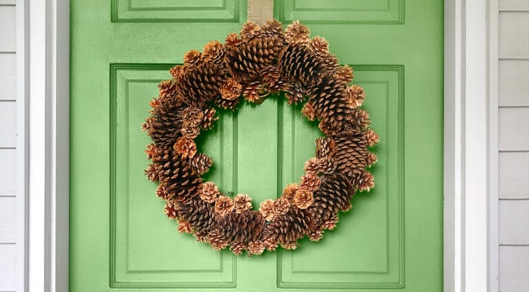 A pinecone wreath hung on a green door.