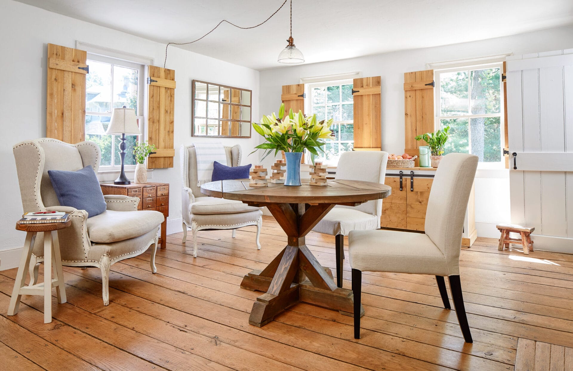 A living room with a dining table and four cream-colored chairs.