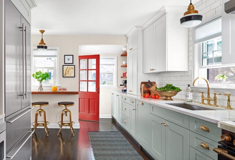 Renovated kitchen with gray base cabinets, white quartz counters and subway tile.
