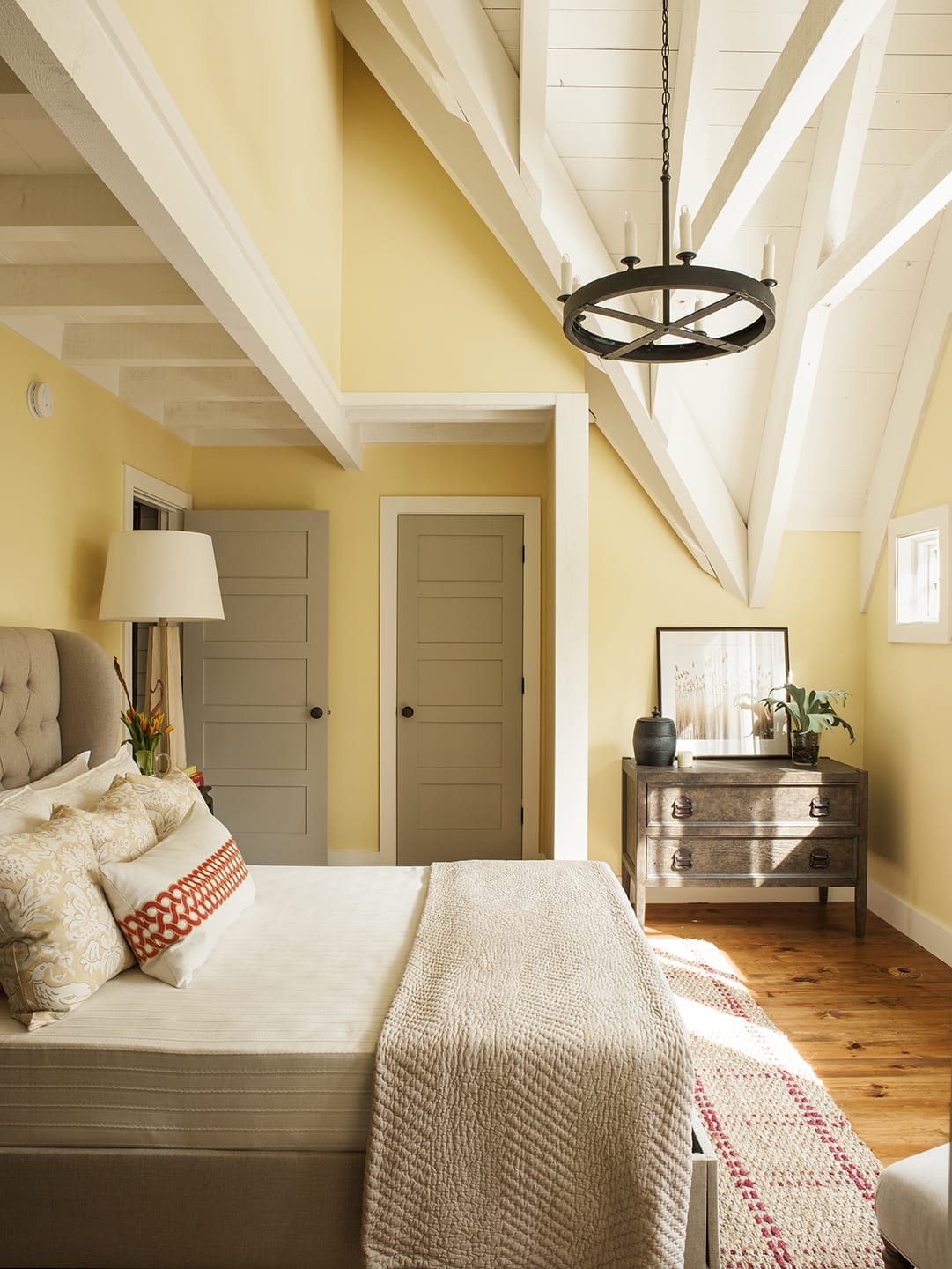 A bedroom with a hanging light fixture and yellow walls.