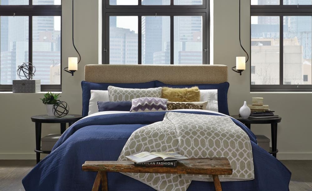 A bedroom overlooking tall buildings in a city.