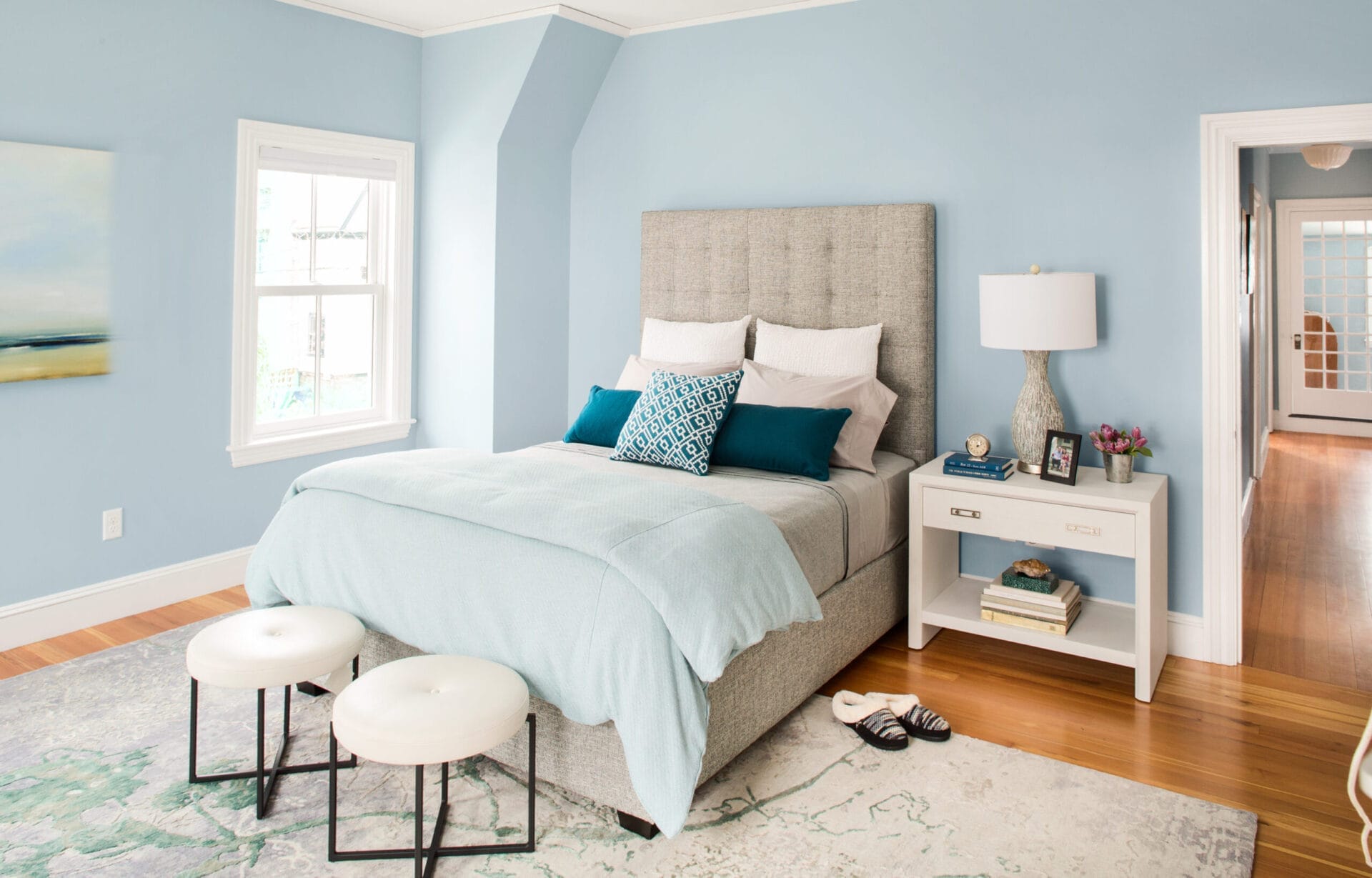 Master bedroom with pale blue walls and neutral furnishings.