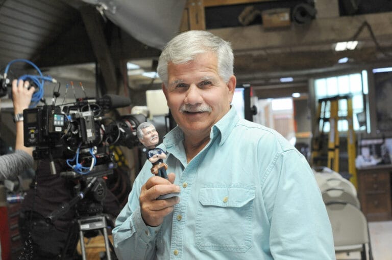 Tom Silva holding a bobblehead trophy award.