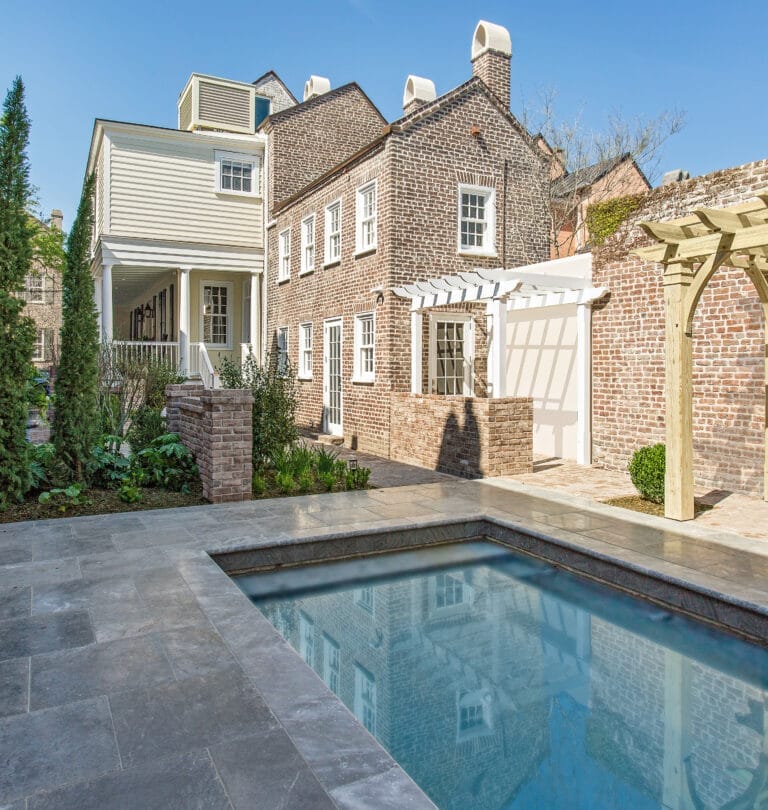Backyard pool area with pergola-covered seating space behind restored kitchen house dining room.