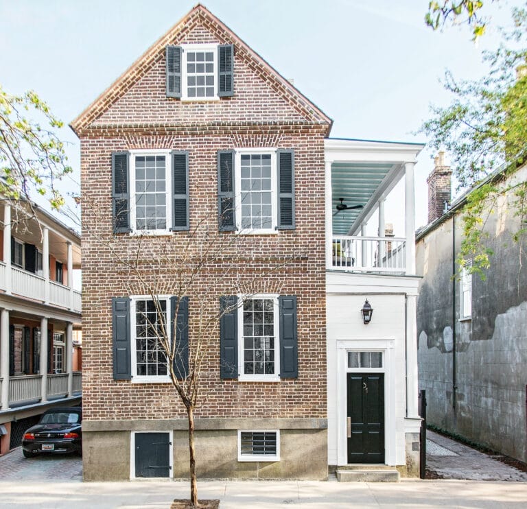Historic Charleston single house front facade showing restored windows, side porches, and traditional shutters.