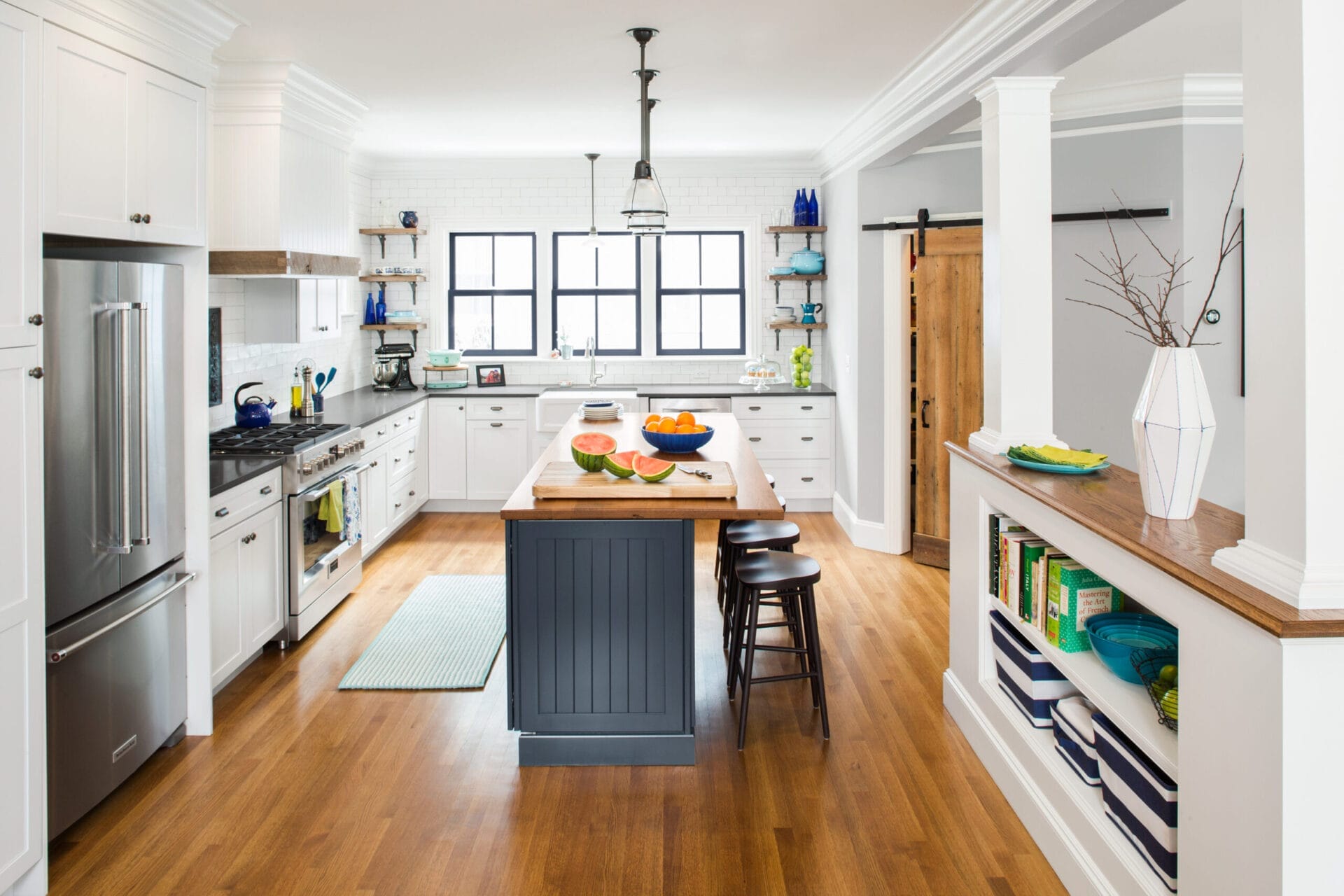 Kitchen with L-shaped layout, white oak floors, and barn-style pantry door.