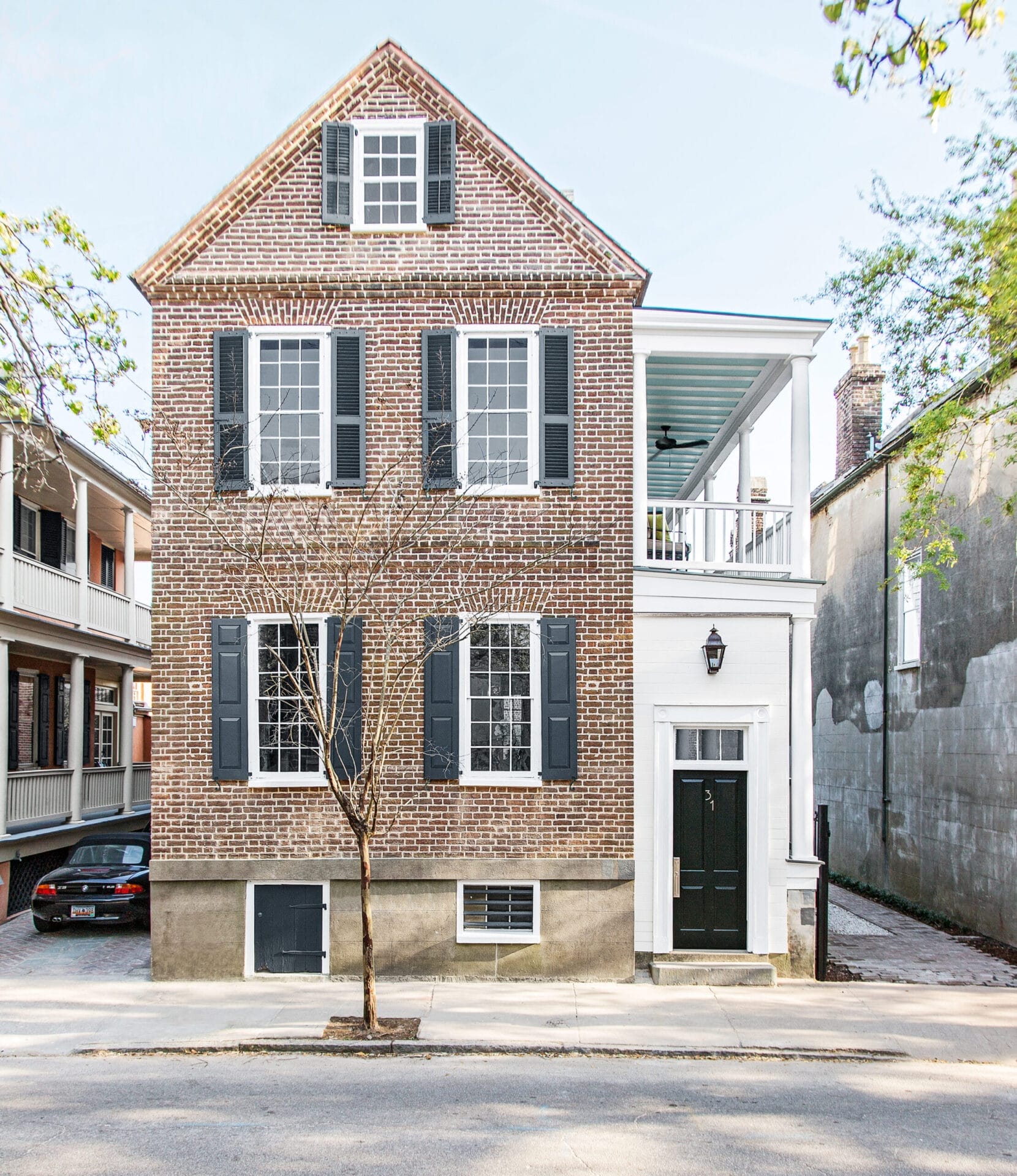 Restored 1840s Charleston Single House with traditional side porches and brick construction.