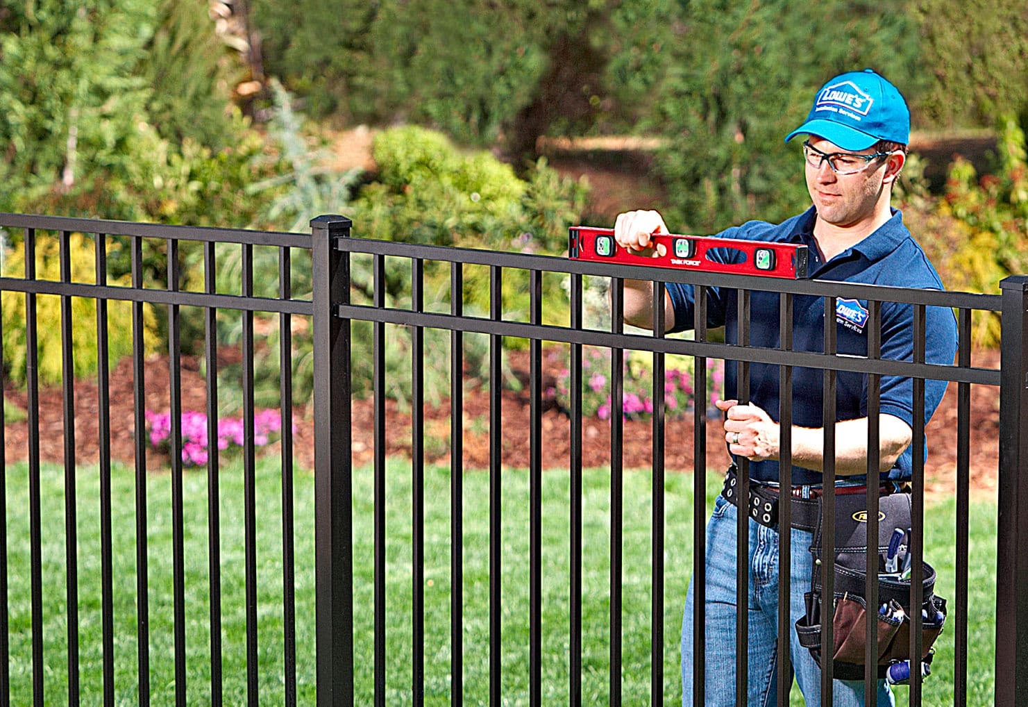 A professional fencer using level while installing a fence.