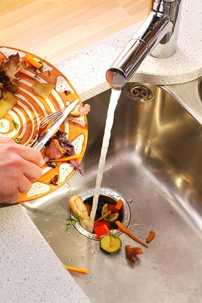 Someone putting scraps into a garbage disposal