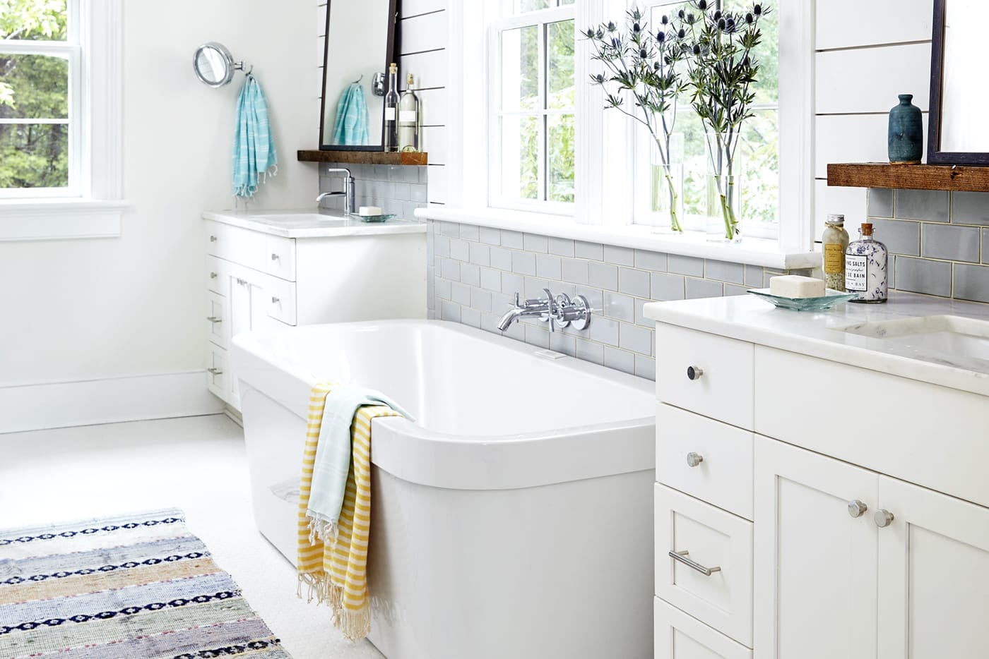 Freestanding soaking tub flanked by twin vanities.