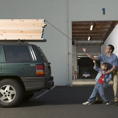 A man and his son putting lumber on top of a car