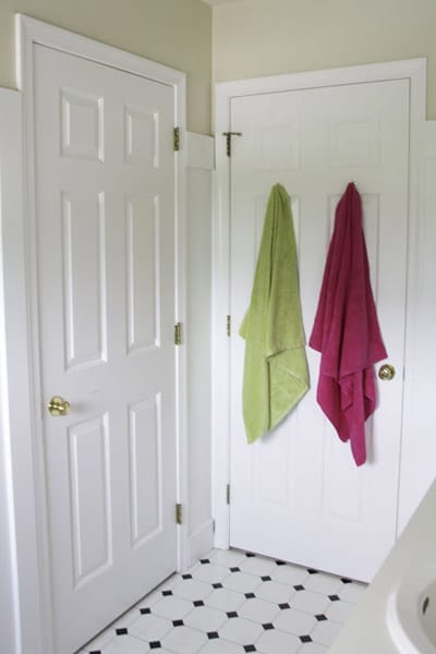 Towels hanging on the back of a bathroom door.
