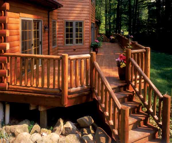 A large wood deck stained to match the color of the log cabin it's attached to.