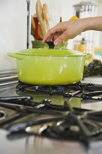 A green pot on a gas stove burner
