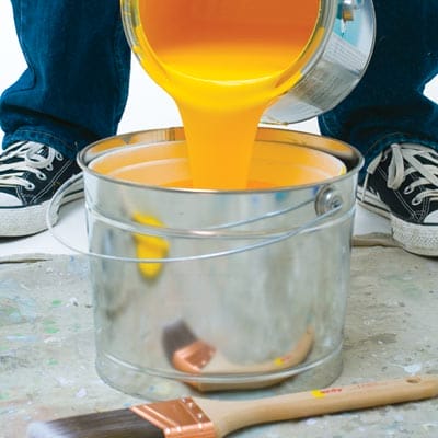 Pouring yellow paint into a bucket