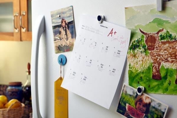 A refrigerator with several pictures and papers affixed to it by magnets.