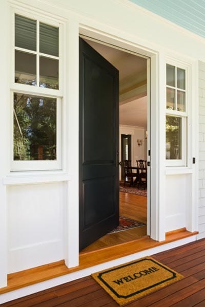 A door in front of a welcome mat sitting halfway open.