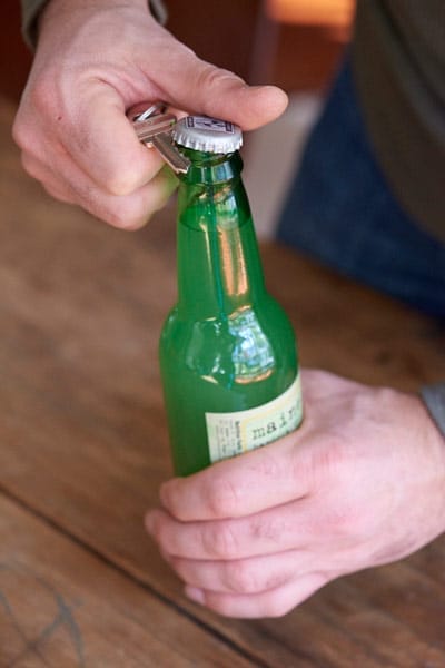 A man using a key as a bottleopener