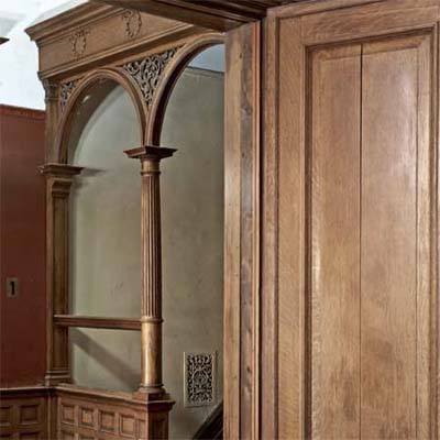 Oak wainscoting, doors, and columns with triangular spandrel connecting arches.