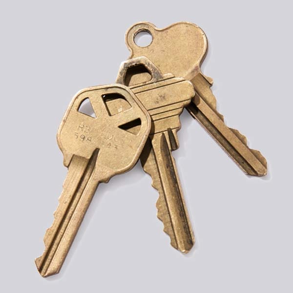 3 House keys against a grey background.