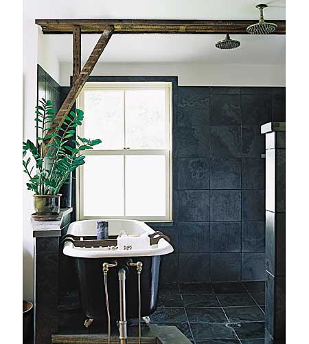 An original bathtub and shower with black slate tile