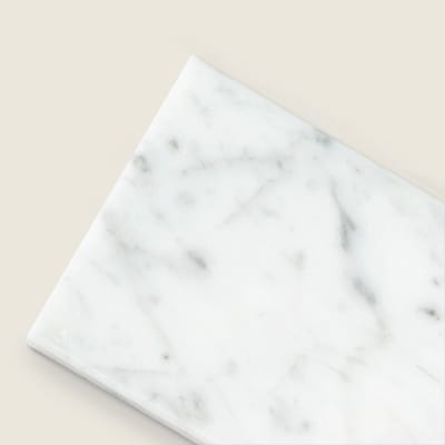 White Carrara marble subway tile with natural stone veining.